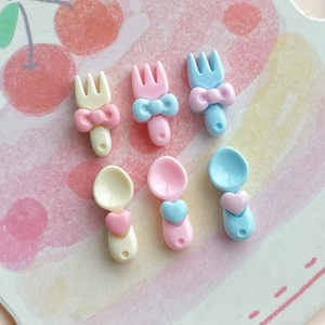 Detailed view of mini resin forks and spoons with heart and bow accents in pastel colors