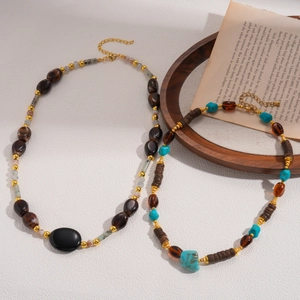 Ethnic acrylic beaded oval pendant necklace with vintage beads on a wooden tray