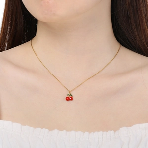 Cute red cherry pendant necklace in gold stainless steel shown on model neckline