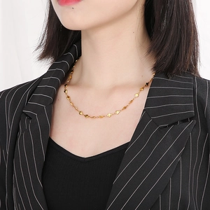 Close-up of minimalist heart necklace in gold worn by a model in a black suit