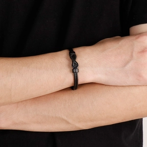 Close-up of black infinity knot bracelet with double woven wire cable on male model wrist