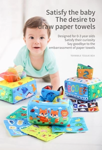 Infant reaching for soft tissue box toy set with colorful learning fabrics and animal prints