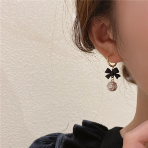 Macro view of C-shaped earrings with black bow knot and clear crystal ball charm
