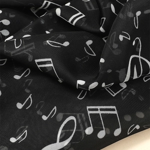 Detailed macro view of black chiffon scarf fabric with white music note prints