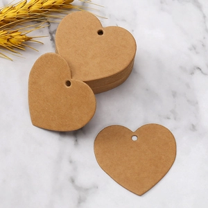 Heart-shaped kraft paper gift tags with hanging holes on white marble background
