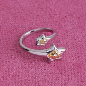 Macro de bague étoile argentée avec centre doré et cristaux sur fond rose