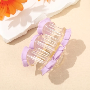 Detailed shot of a purple flower hair claw clip with a transparent yellow body on stones