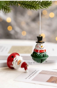 Detailed view of metal snowman and Santa bell ornaments hanging on a Christmas tree