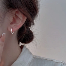 Close-up of a silver hoop earring with tassel chain on model's ear in minimalist style