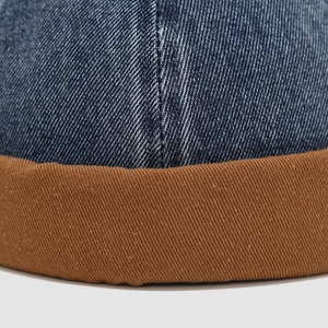 Detail der blauen Denim- und braunen Canvas-Nähte an der Kinder Docker Mütze