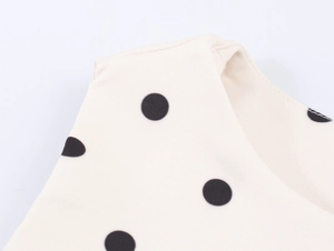 Close-up of cream cotton-linen fabric with black polka dots on sleeveless vest top