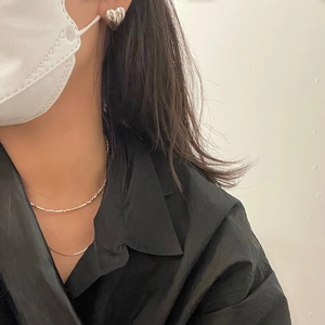 Close-up of heart-shaped silver earrings and a shimmering thin chain necklace on a model