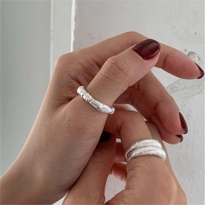 Detailed view of layered 925 sterling silver knot and frosted rings on fingers