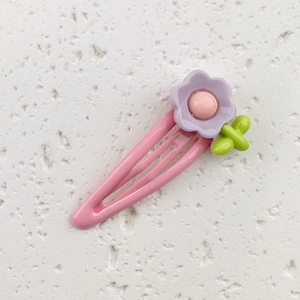 Detail of pink metal hair clip with purple resin flower and green leaf ornament