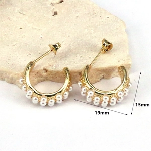 Detailed macro view of gold C-shaped earrings with double row pearl inlays and 19mm width
