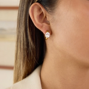 Close-up van gouden roestvrijstalen oorbellen met ovale zirkonia stenen op een model