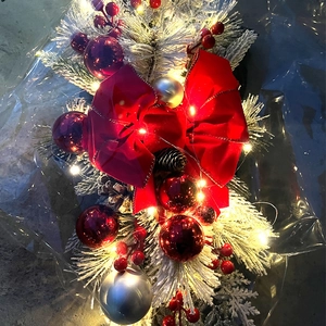 Detailed view of pre-lit Christmas swag with red bows, pine cones, and snowy flocked pine