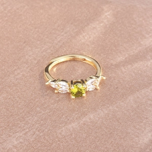 Detail of olive green zircon ring with marquise diamonds on silk background