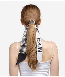 Detail of black and white houndstooth hair ribbon with RAIN lettering tied on a ponytail