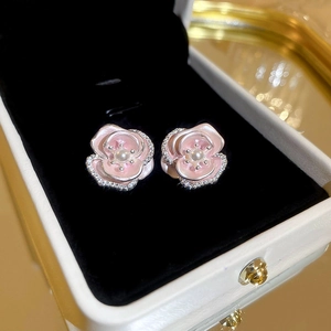 Macro shot of pink enamel camellia studs with a center pearl and zircon accents