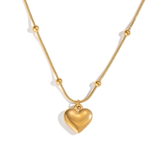 Détail du pendentif cœur doré avec chaîne à billes sur un fond blanc éclatant