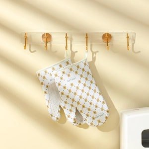 Floral heat resistant oven mitts with non-slip silicone palms hanging on gold hooks