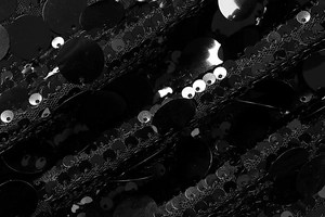 Detailed macro view of shimmering black sequins sewn on delicate mesh dress fabric