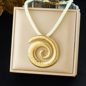 Gros plan d'un pendentif spirale doré sur cordon tressé posé sur un écrin à bijoux