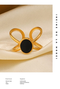 Close-up of golden 18K plated ring with black oval enamel on elegant cream silk fabric