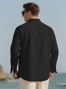 Back view of men's black linen shirt with standing collar shown in a seaside setting