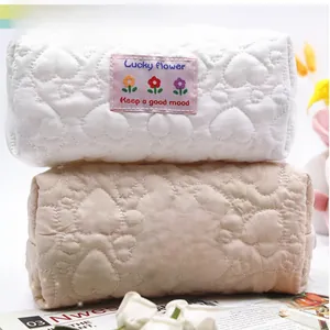 Close-up of heart-quilted floral pencil cases in cream and beige with soft silk labels