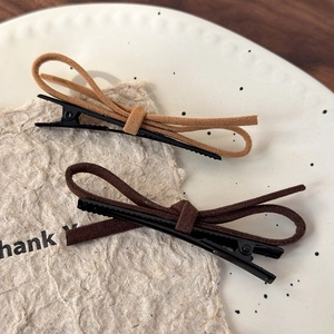 Detail of red suede bow hair clips in light and dark brown on an elegant beige plate