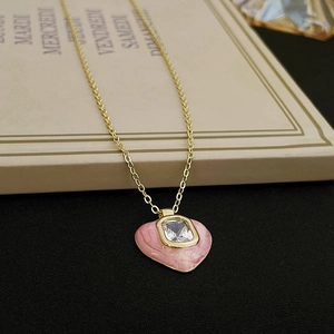 Detail of a pink enamel heart pendant with square zircon on a golden chain necklace