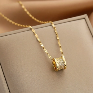 Elegant gold titanium necklace with a crystal-encrusted cylinder pendant on silk