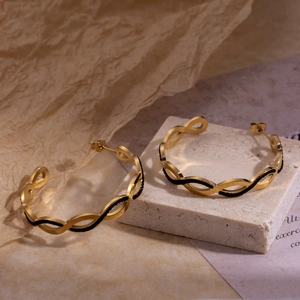 French vintage C-shaped gold hoop earrings with black wave texture on a stone base