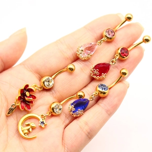 Vista dettagliata di vari piercing all'ombelico placcati in oro con strass colorati a goccia