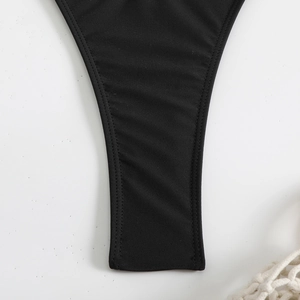 Dettaglio dello slip bikini nero che mostra il tessuto elasticizzato e le cuciture piatte