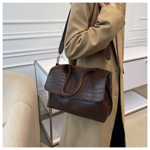 Detail of brown crocodile pattern leather shoulder bag with adjustable strap and large capacity