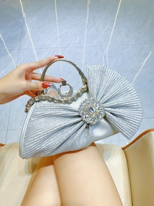 Detail of silver sequined evening bag featuring a crystal bow and rhinestone handle