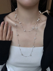 Close-up of double-layer necklace with white round pearls and fine silver-tone chain