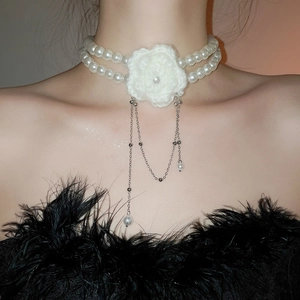 Gros plan sur un choker en perles double rang avec fleur au crochet et pompons