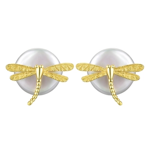 Close-up of golden dragonfly earring with brushed texture and white round pearl