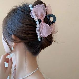 Detail of pink mesh bow hair claw with pearls and crystals on a model's ponytail