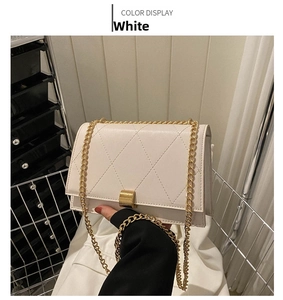 Close-up of white quilted crossbody bag with gold square clasp and fine chain strap