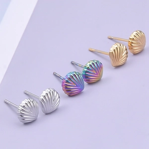 Macro view of seashell stud earrings in silver, gold, and rainbow finishes on purple background