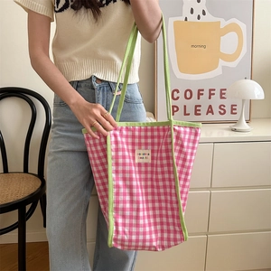 Detaillierte Nahaufnahme der rosa karierten Canvas-Tasche mit grünen Riemen und Akzenten