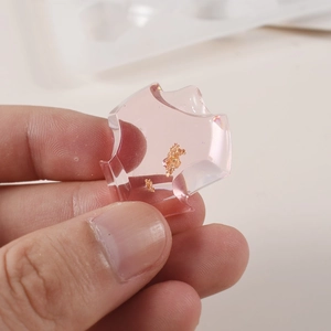 Detailopname van doorschijnende roze hars hanger met goudfolie en glanzende afwerking