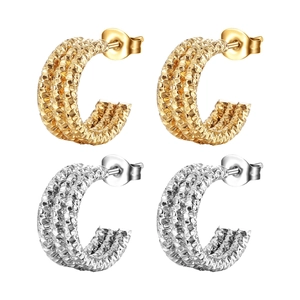 Detailed macro shot of textured C-shape earrings in polished gold and silver steel finish