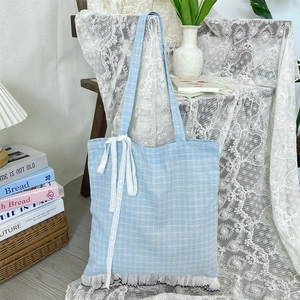 Detail of light blue checkered tote bag featuring white lace ribbons and layered frills