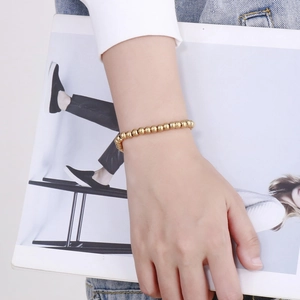 Détail d'un bracelet à perles plaqué or 18 carats au poignet avec magazine de mode